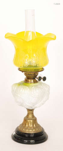 A Victorian oil lamp and yellow etched shade with moulded and embossed reservoir on black glazed base