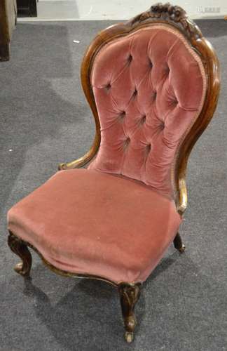 A Victorian carved walnut framed easy chair upholstered in pale pink buttoned back plush