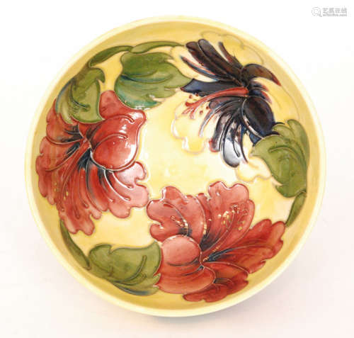 A Moorcroft footed bowl decorated in the Hibiscus pattern with tubelined flowers against a yellow wash ground