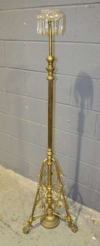 A late Victorian brass standard lamp with clear crystal tier drop on pierced aesthetic style base ball and claw feet