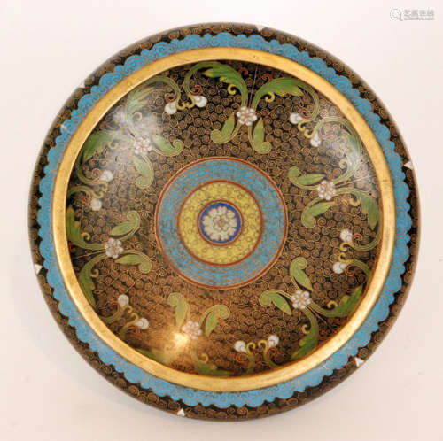 A Chinese cloisonne shallow footed bowl of circular outline with sylised floral and foliate decoration to a black ground with blue border and gilt rim