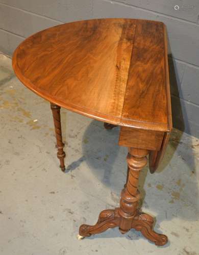 A Victorian oval walnut drop flap Sutherland table on turned scroll ends united by a turned stretcher