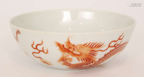 A Chinese shallow bowl decorated to the exterior with two burnt red hand painted dragons chasing two flaming pearls