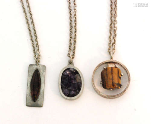 Three Danish pewter pendants by Jorgen Jensen to include a tiger's eye mounted pendant