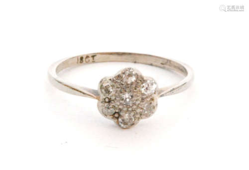 An early 20th Century 18ct white gold diamond daisy cluster ring seven old cut stones to knife edged shoulders