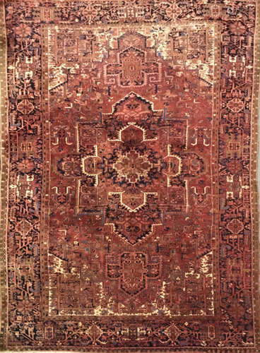 A North West Persian carpet with central red and ivory panel bordered by stylised geometric lozenges