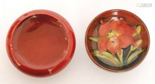 A small Moorcroft footed bowl decorated in the Flambe Freesia pattern with a central flower against a tonal ground