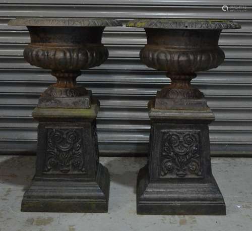 A pair of 19th Century black painted circular cast iron terrace urns of classical form on waisted acanthus panel square plinth bases