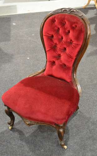 A Victorian carved walnut balloon back easy chair upholstered in buttoned crimson plush