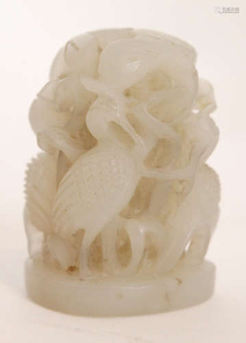 A Chinese celadon jade carving of domed form depicting four standing cranes sheltering amidst scrolling vines and leaves