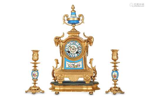 A LATE 19TH CENTURY FRENCH GILT METAL AND PORCELAIN MOUNTED CLOCK GARNITUREthe case surmounted by a twin handled urn and flanked by a pair of ram mask mounts