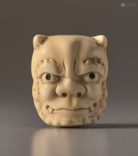 AN IVORY NETSUKE OF A MASK OF AN ONI AND OKAMEI...