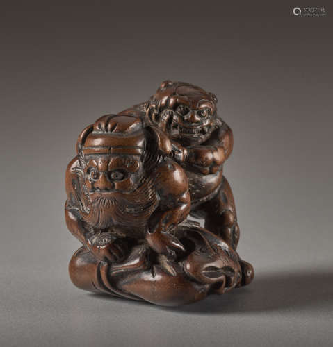 A WOOD NETSUKE OF THE DEMON QUELLER SHOKI WITH ONI...