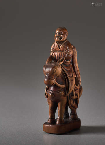 A WOOD NETSUKE OF TOBA SEATED ON HIS MULEWood n...