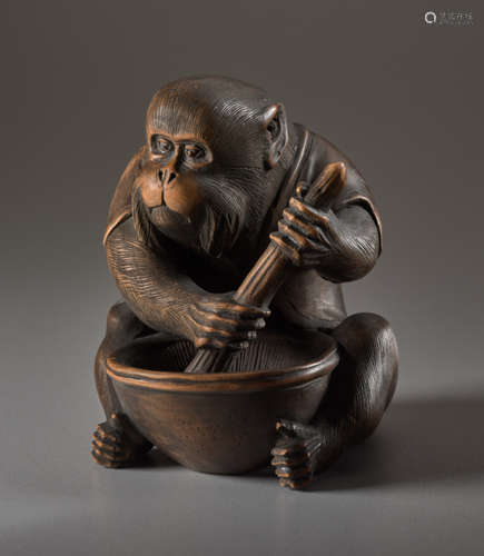 A WOOD OKIMONO BY JIGO OF A MONKEY STIRRING MISO...