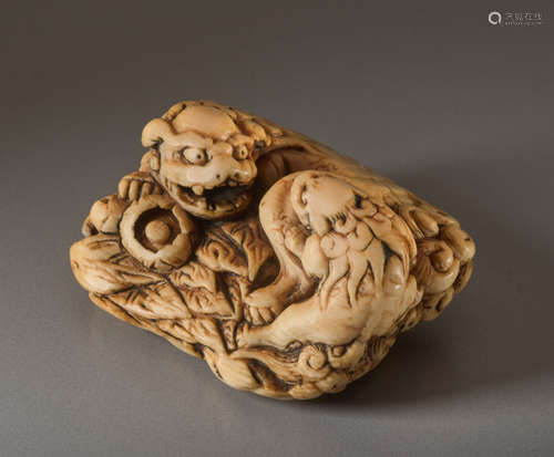 AN IVORY NETSUKE OF A SHISHI WITH PUPPYIvory ne...