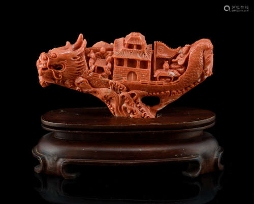 A RED CORAL CARVING OF A DRAGON BOAT WITH PASSENGERS