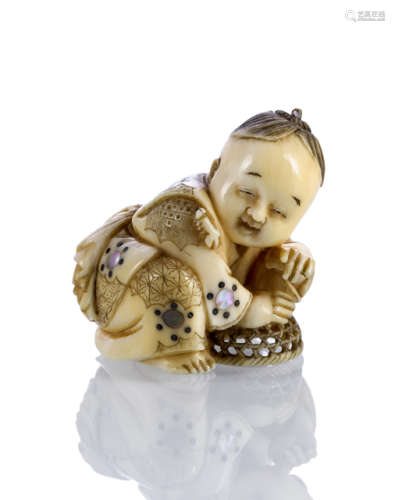 A FINE CARVED IVORY NETSUKE OF A BOY PLAYING WITH A CATERPILLAR WITH MOTHER OF PEARL INLAYS