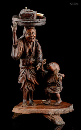 A CARVED WOOD OKIMONO OF AN OLD PEASANT WOMAN SELLING TEA ACCOMPANIED BY A YOUNG BOY