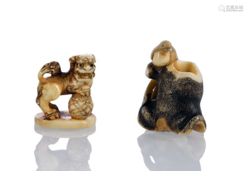 TWO CARVED IVORY NETSUKE: A BIRD NEAR A TREE TRUNK AND A BUDDHIST LION WITH BALL