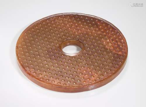 AN ATTRACTIVE AMBER COLOURED BI DISC WITH A PATTERN OF RAISED BOSSES