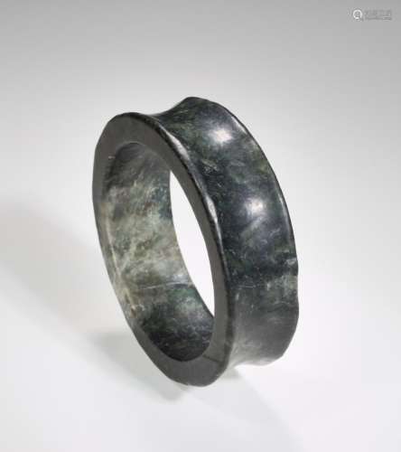 AN ELEGANT NEOLITHIC BRACELET IN DARK GREEN JADE WITH A SMOOTH CONCAVE BORDER