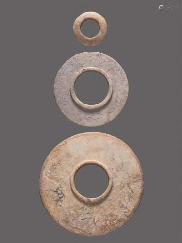 A GROUP OF TWO HEAVILY ALTERED SHANG PERIOD JADE DISCS AND A RING, ALL WITH A BEAUTIFUL CRYSTALLINE SOUND