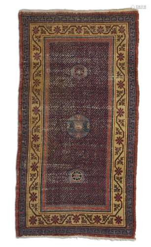 An antique Khotan rug, East Turkestan. Three medallions on a fretted field. Early 19th century. 237 x 127 cm.