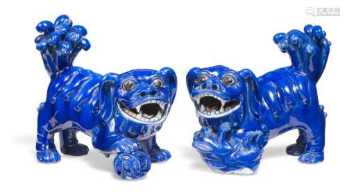 A pair of porcelain Fo-dogs in blue glaze, the he with a ball under the paw and the she with a puppy under the paw. 19th century.