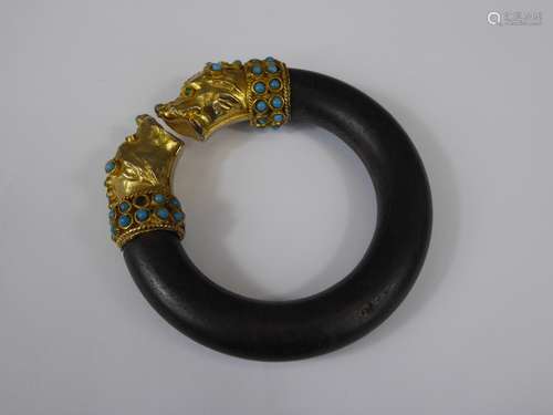 A Wooden Bangle, with gilded dog-head finials set with turquoise.