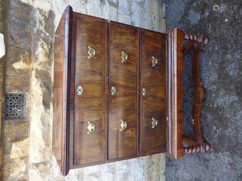 Antique Walnut Veneered Chest on Stand; the chest having three long drawers with brass batwing handles, raised on turned legs and shaped stretchers, approx 100 x 50 x 123 cms high.