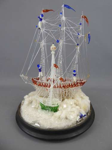 A 19th Century Nailsea Glass Frigger, Pilot Boat and Lighthouse, presented in a glass dome, the ship measures approx 27 cms and the dome 35 cms. formed as a three mast sailing ship with sailors amongst the rigging.