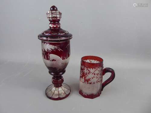 A Victorian Bohemian Cut Glass Ruby Jar and Cover, beautifully etched with a woodland scene depicting deer grazing, approx 30 cms, together with a tankard of similar design. (2)