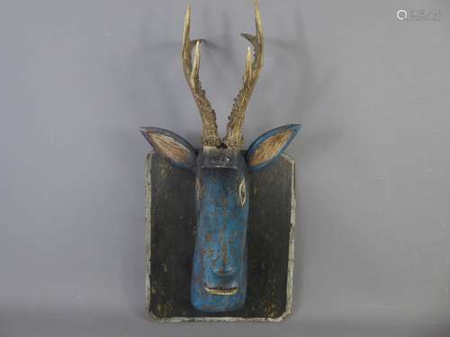 A Vintage Hand-Carved Wooden Folk Art Deer Head with real Antlers, mounted on a rectangular wooden shield, in original blue paint, approx 48 cms to tip of antlers.