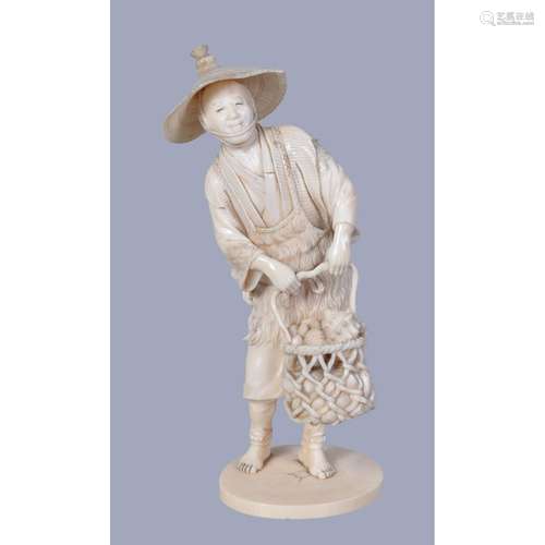 A Japanese Ivory Okimono carved as a standing fisherman wearing a reed apron and a broad straw hat as he lifts a large basket of shells