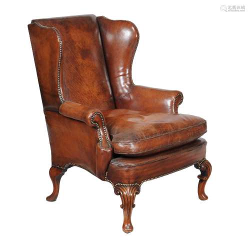 A mahogany and brown leather upholstered wing armchair