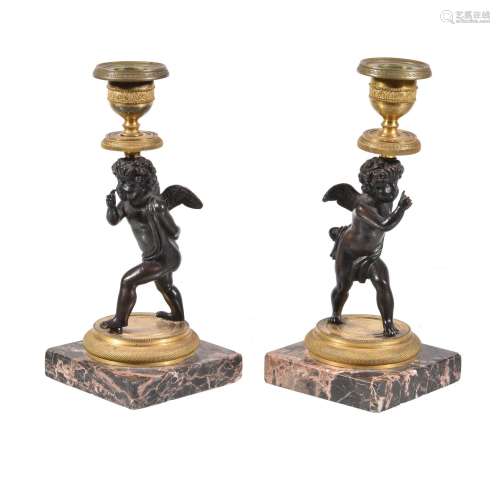 A pair of Charles X or Louis Philippe patinated and gilt bronze figural candlesticks