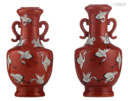 A pair of Chinese coral red ground baluster shaped vases, decorated with cranes, with a Qianlong mark, H 16 - 17 cm