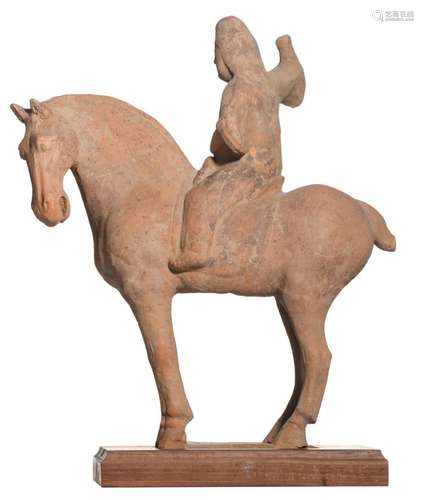 A Chinese red earthenware sculpture depicting a horseman, traces of polychrome paint, on a wooden base, probably Tang dynasty, H 32,5 cm (without base)