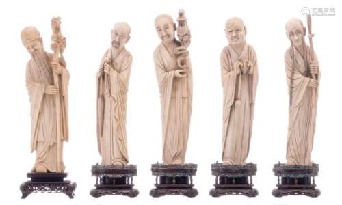 A series of four Chinese ivory figures depicting four of the Immortals, the base of exotic hardwood with silver inlay and the metal mounts cloisonné decorated, 19thC; added a ditto ivory figure on a sculpted exotic hardwood base, late 19th - early 20thC, H 30,5 - 32,8 cm - Individual weight of the figures: 767 - 833 - 834 - 865 - 932g