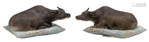 A pair of Chinese polychrome biscuit buffalo's on a matching broderie pillow, marked, H 10,5 - 10,3 cm