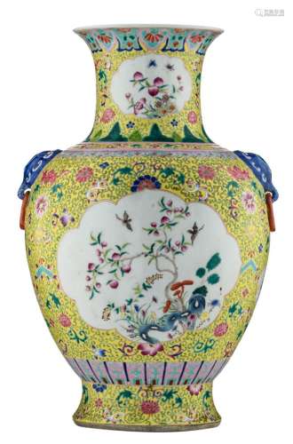 A Chinese yellow ground famille rose floral decorated vase, the roundels with birds, butterflies and flower branches, the handles elephant head shaped, with a Qianlong mark, H 56,5 cm