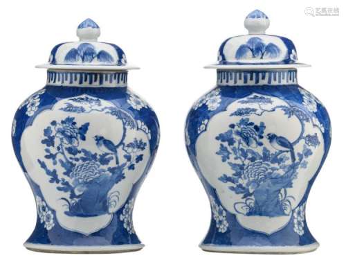 Two Chinese blue and white floral decorated vases and covers, the roundels with a rock and a bird on flower branches, with a Kangxi mark, H 36 cm