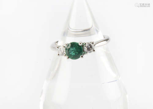 A modern 18ct white gold three stone emerald and diamond ring