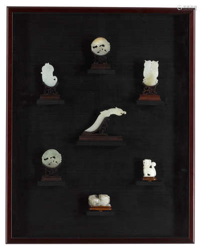 A shadow box of seven mounted jade and hardstone carvings