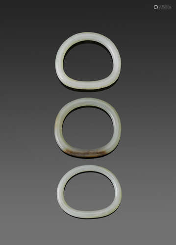 a group of Three jade bangles of irregular oval shape