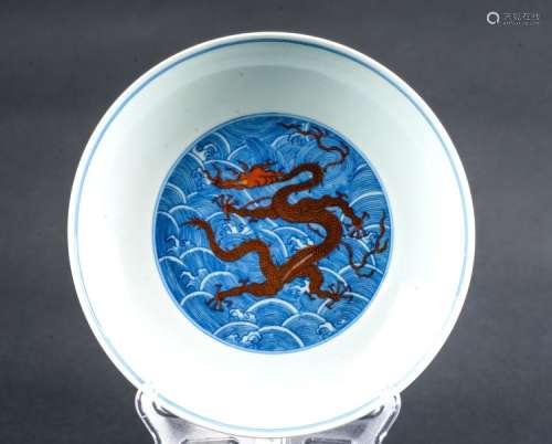 Chinese Art A blue and white dish painted with a red dragon among waves and bearing a six character Qianlong seal mark at the base China, 20th century