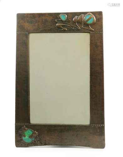 A patinated copper wall mirror possibly retailed by Liberty & Co