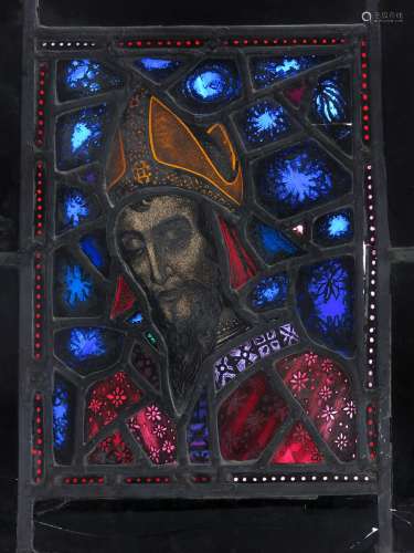 A stained glass panel of a saint in the manner of Harry Clarke