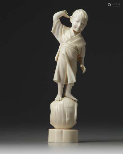 An ivory carving of a young boy standing on a large vase